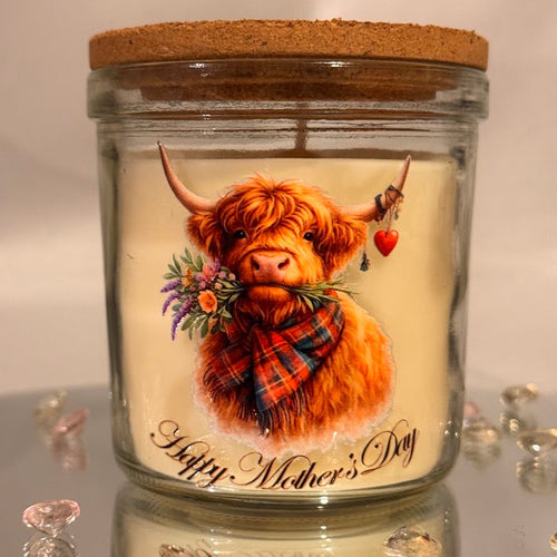 Glass candle jar with a highland cow illustration and 'Happy Mother's Day' text on a reflective surface.